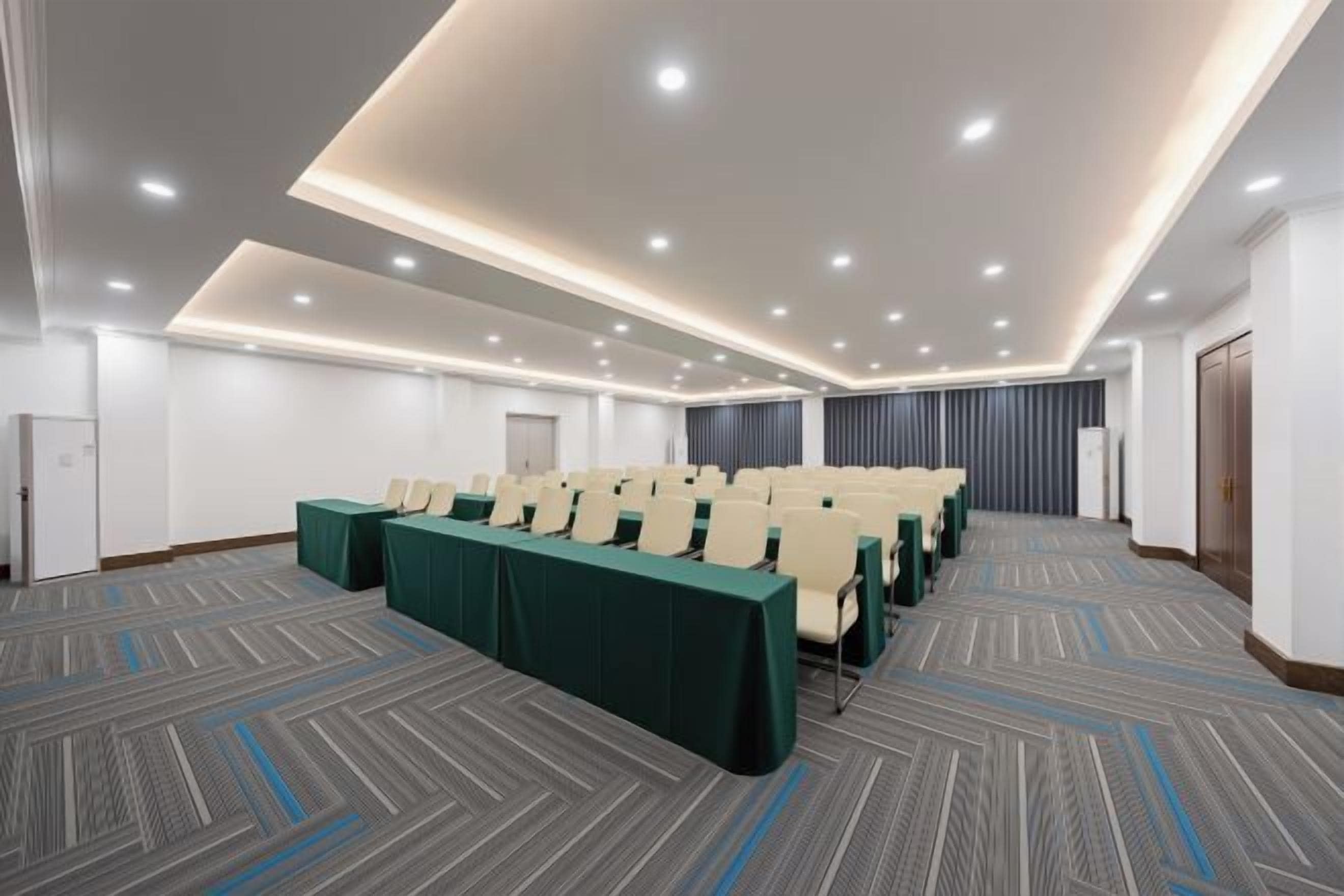 A conference room with rows of chairs, a carpeted floor, and recessed ceiling lighting.