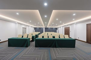 Un salón de conferencias con una mesa larga, sillas y piso alfombrado.
