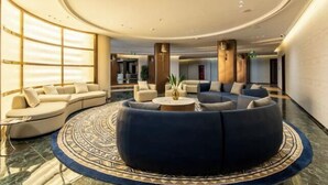 Eine moderne Lobby mit einer runden Sitzecke, einem großen Fenster mit Jalousien und einem Marmorboden.