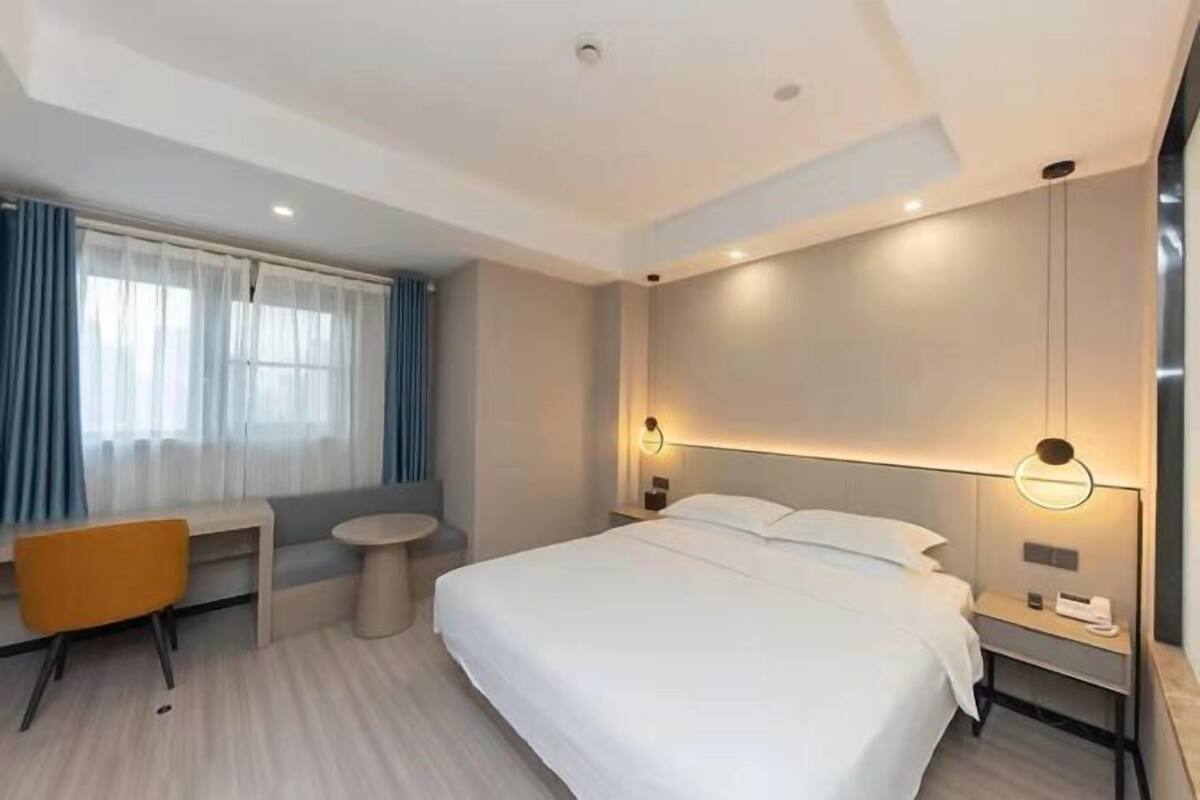 Una habitación de hotel moderna con una cama grande, un escritorio, una silla y una pequeña mesa redonda.