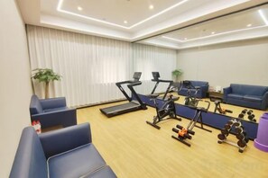 A fitness room with exercise equipment, seating, and a large mirror. - Huali Hotel (Kunshan Golden Eagle International Shopping Center) (Kunshan)