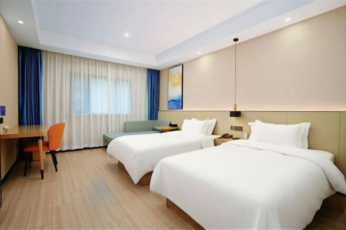 Habitación de hotel con dos camas, un escritorio y una silla.