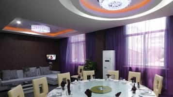 A conference room with a round table, chairs, and a television on the wall.