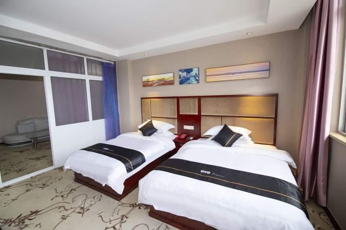 Habitación de hotel con dos camas, un espejo grande y vista a la ciudad.