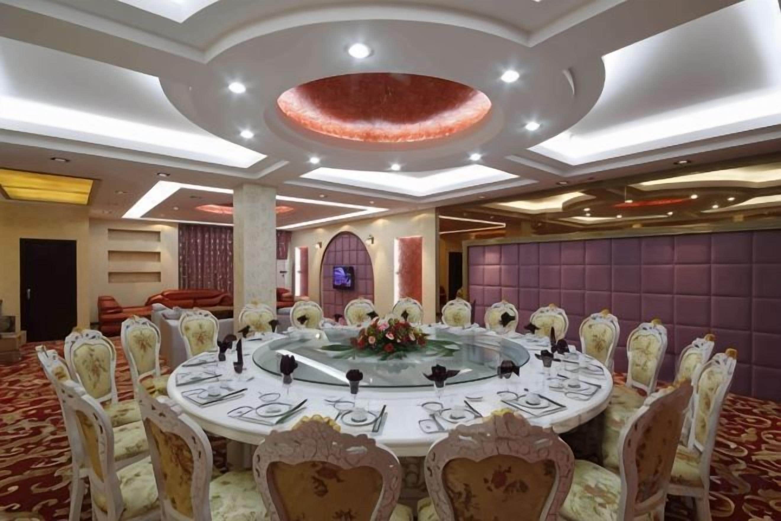 A round dining table with chairs, a glass centerpiece, and a red accent on the ceiling.