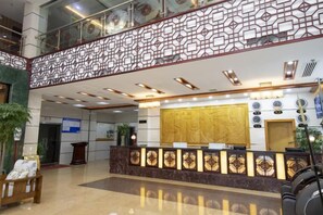 A hotel reception area with a reception desk, a decorative ceiling, and a large window. - Great Wall Hotel (Wuyuan High-speed Railway Station) (Wuyuan)