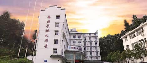 A multi-story hotel with a prominent entrance and a parking area.