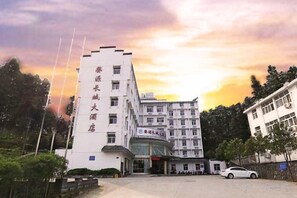A multi-story hotel with a prominent entrance and a parking area. - Great Wall Hotel (Wuyuan High-speed Railway Station) (Wuyuan)