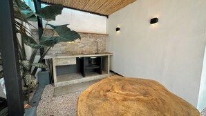 A modern kitchen with a brick backsplash, a large wooden table, and a hanging plant.