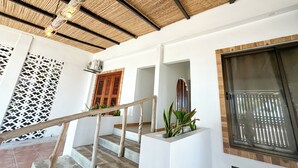 A staircase with a wooden handrail, a ceiling with a woven pattern, and a wall-mounted air conditioning unit.