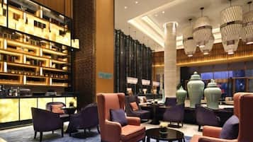 A lobby with a bar area, seating, and a large vase.