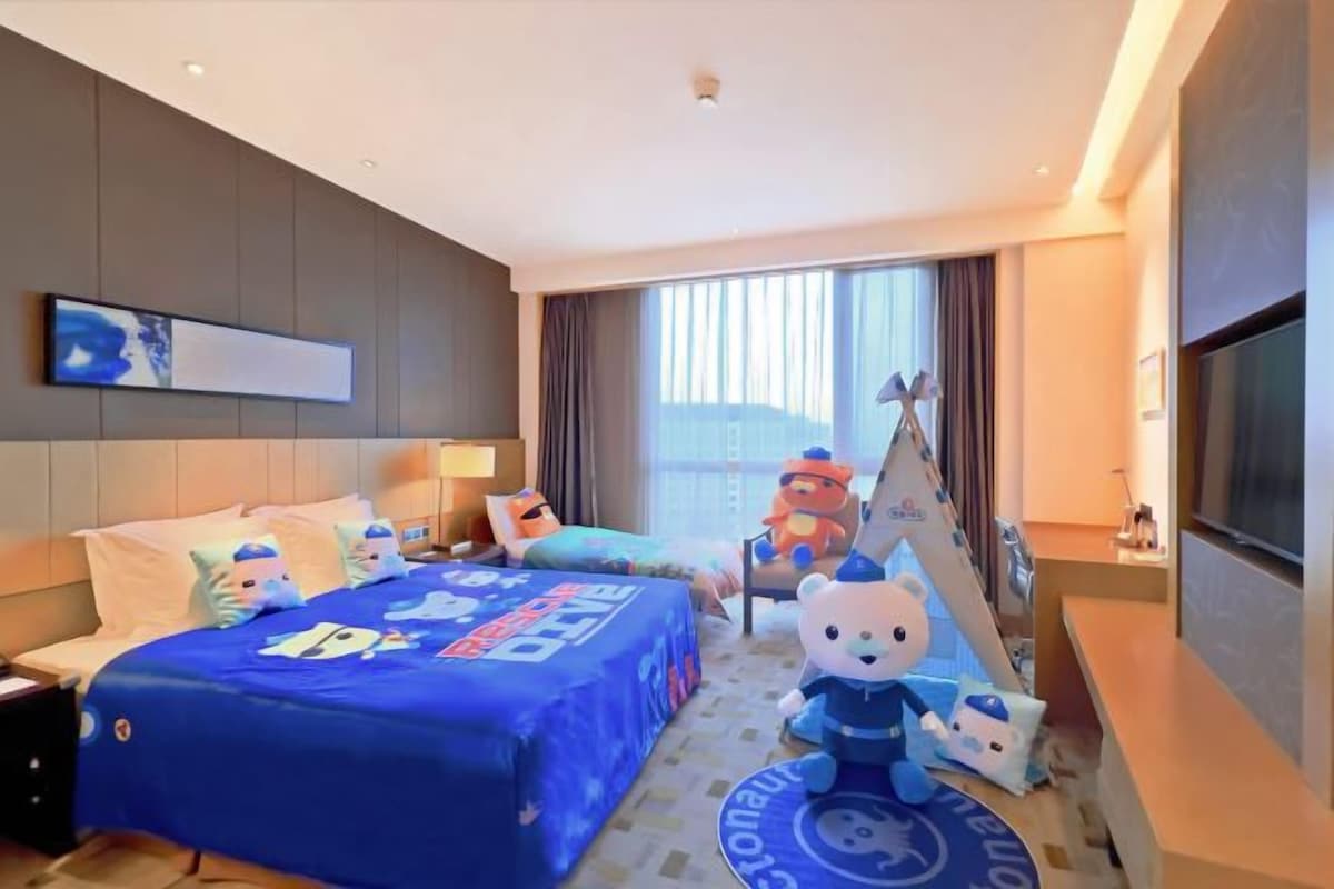 Una habitación de hotel con una cama grande, televisión y ventana con cortinas.