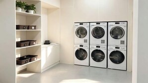 A laundry room with four stacked washing machines, a shelf with potted plants, and storage bins. - Steigenberger Nanchang Sunac (Nanchang)