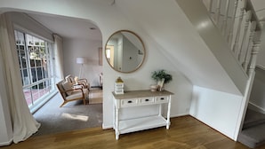 A room with a wooden floor, a white console table with drawers, a round mirror, and a staircase with white balusters. - SERENITY STAYS: Best price for value - 5 min from beach, cafes and racecourse (Mount Martha)