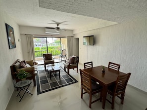 Relax in a spacious room with a dining area, sofa, and large window offering a view of the outdoors.