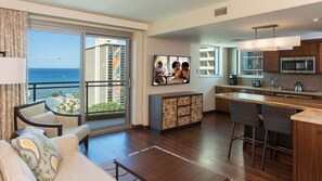Ein modernes Hotelzimmer mit Balkon, einer Küche mit Bar und einem Essbereich.