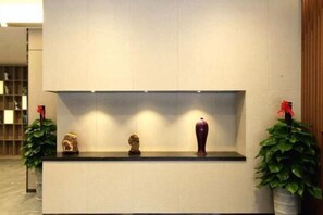 Reception area with a minimalist design, featuring a reception desk and decorative items on display.