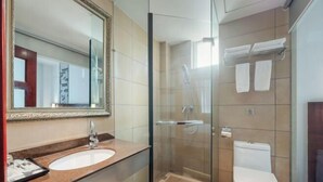 Une salle de bain moderne avec une douche à parois de verre, un lavabo blanc et des toilettes.