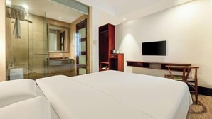Une chambre d’hôtel avec un lit, un bureau, une télévision, une douche et un miroir.
