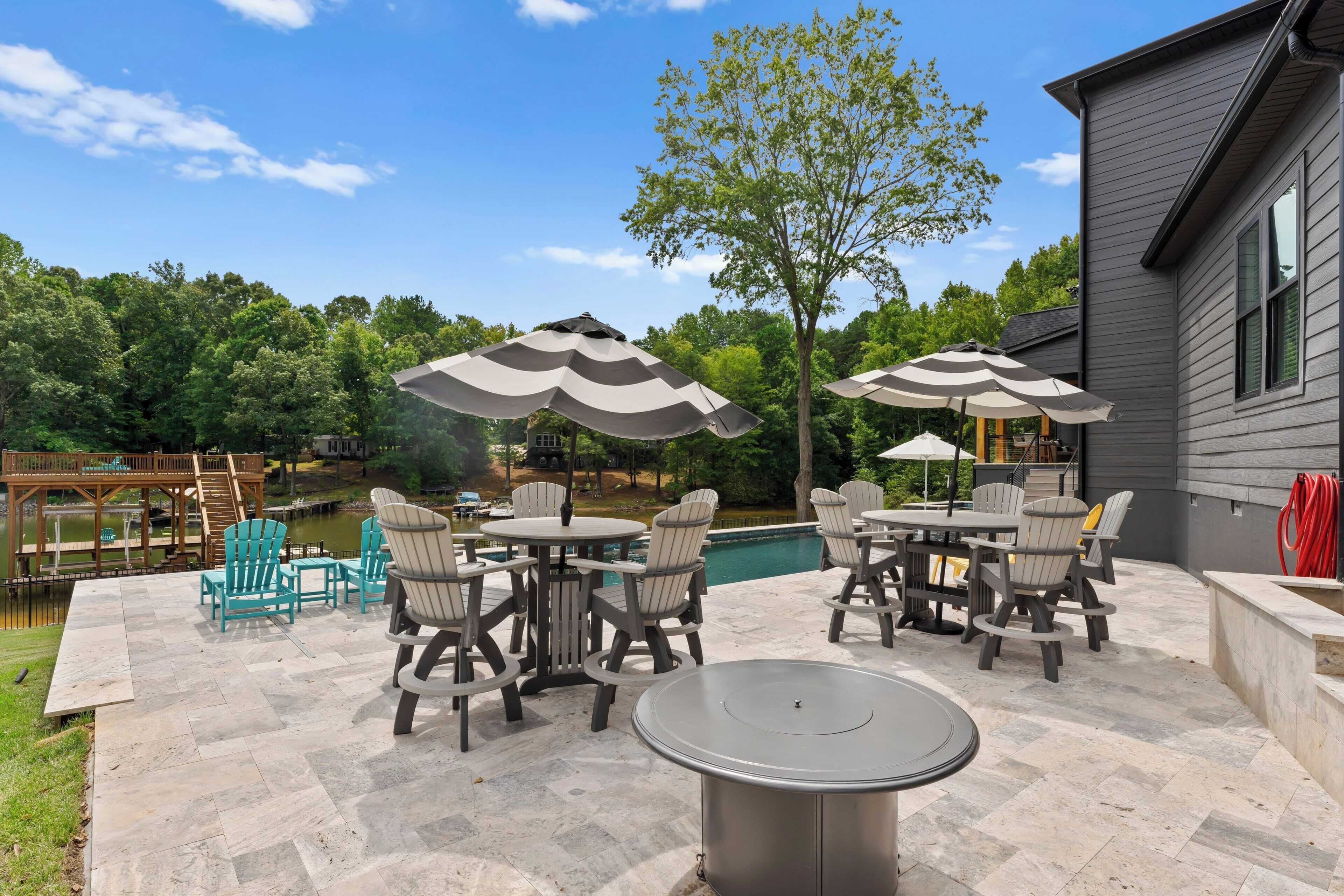 Eine Außenpatio mit Pool, umgeben von Adirondack-Stühlen und Tischen, sowie eine Holzterrasse mit Blick auf den Pool.