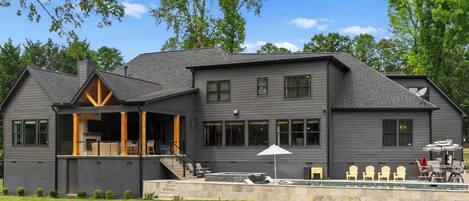 A two-story house with a covered patio, a swimming pool, and a well-maintained lawn.