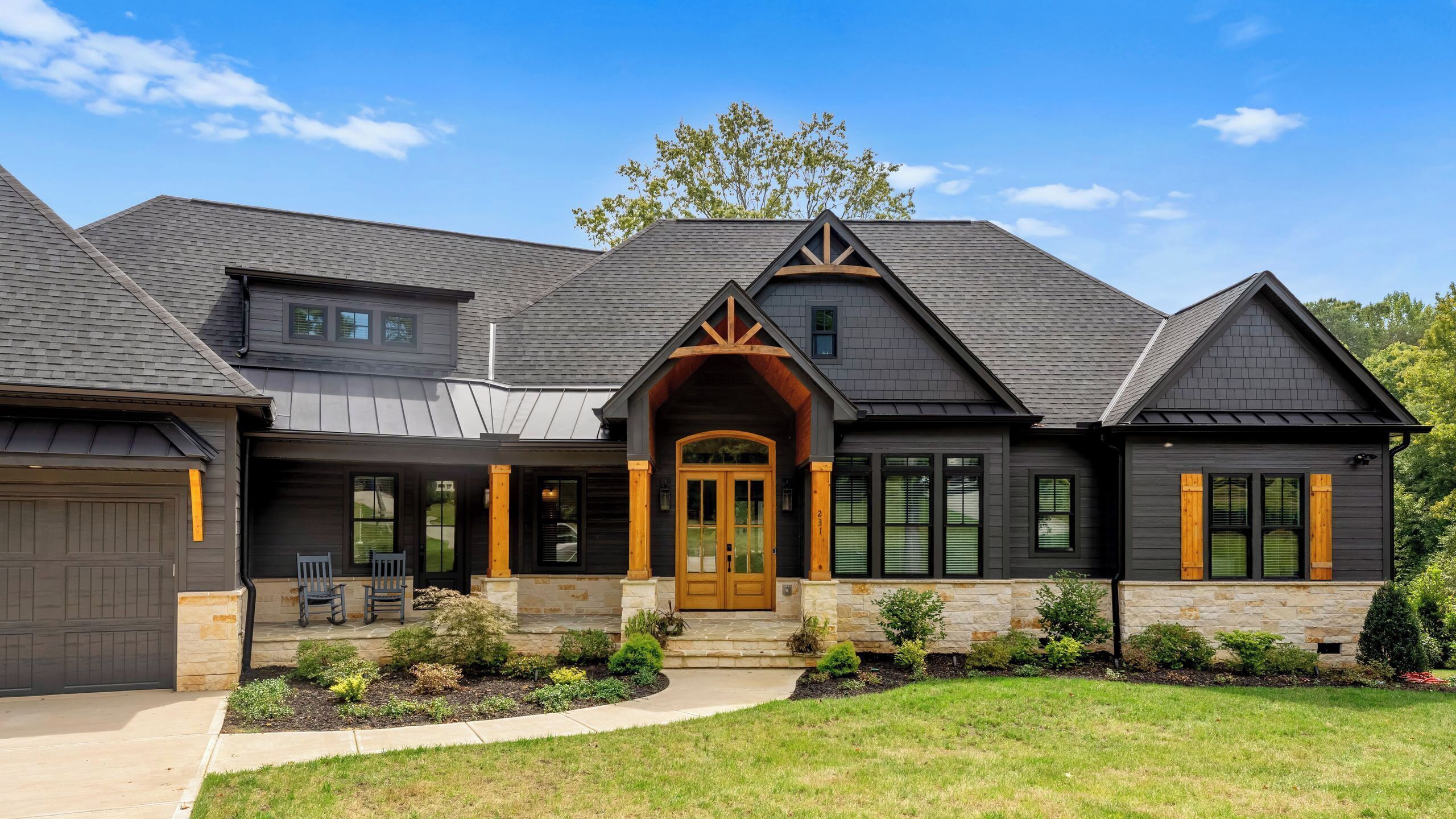 A two-story house with a prominent front entrance, stone foundation, and a well-maintained lawn.