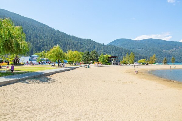 A beach with a sandy shore, trees, and a mountain in the background.