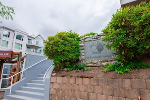 Un rètol de pedra amb la inscripció “Echo Beach Resort 328 Esplanade Avenue” envoltat de vegetació.