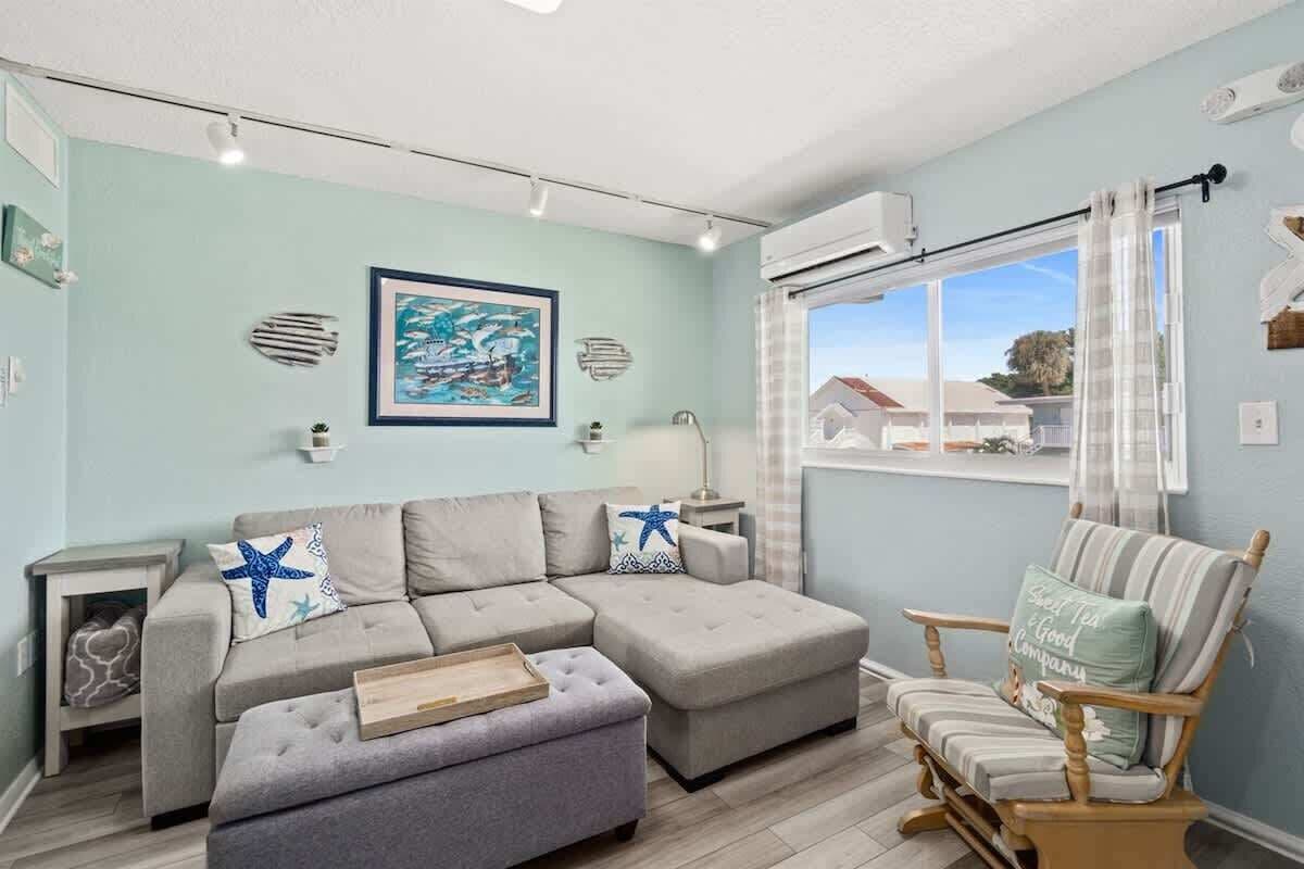 A living room with a sectional sofa, a wooden coffee table, a rocking chair, and a window with curtains.