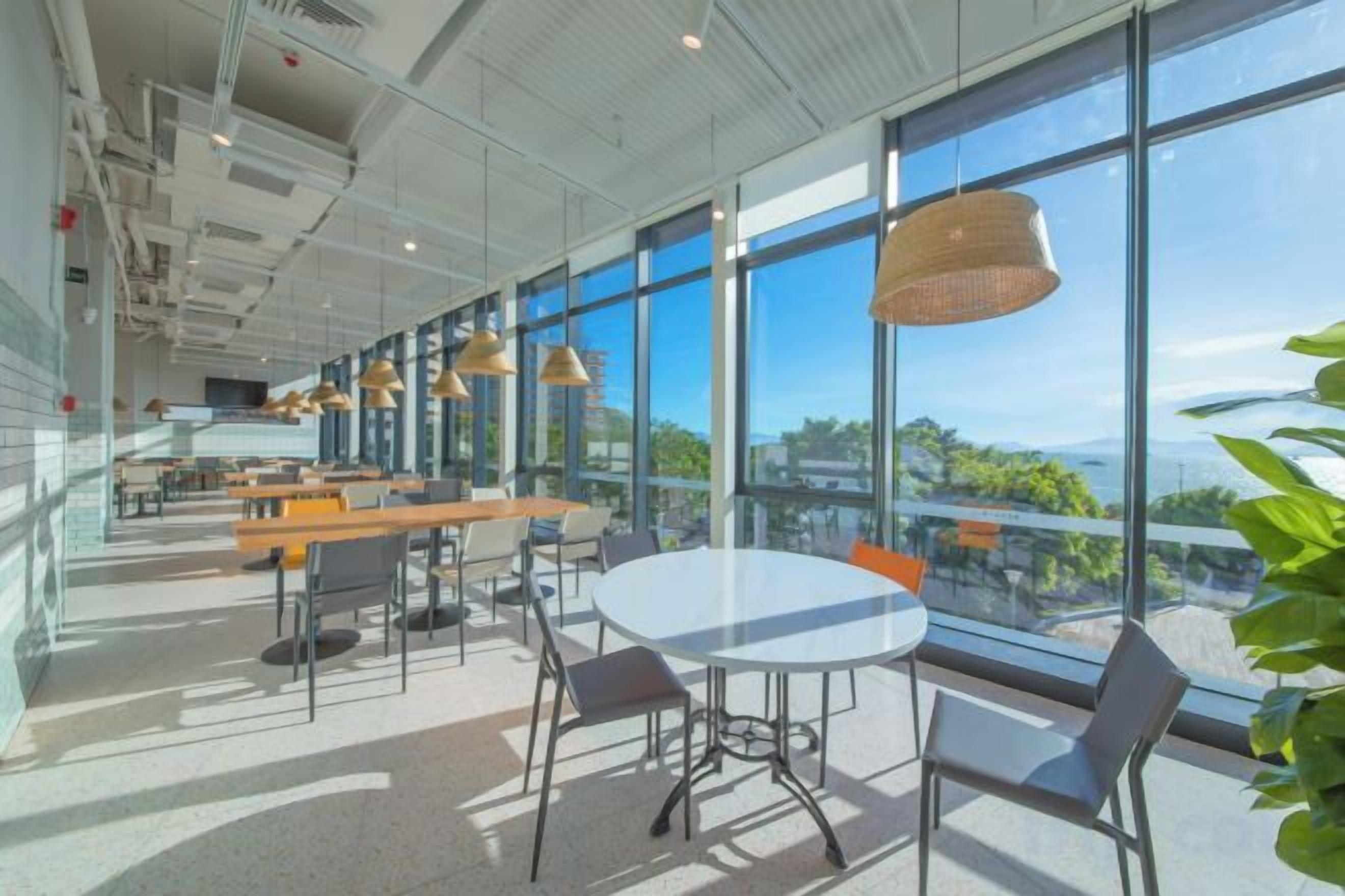 A modern interior with large windows, a round table, and multiple seating arrangements.