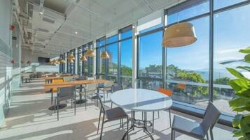 A modern interior with large windows, a round table, and multiple seating arrangements.