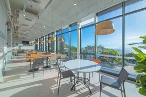 A modern interior with large windows, a round table, and multiple seating arrangements. - Island Skylight Resort (Huidong)