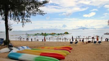 A beach with canoes lined up and a group of people in the water.