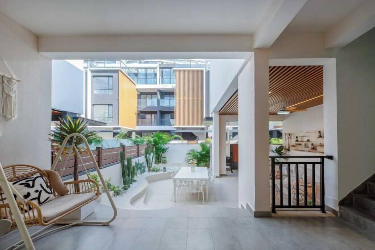 An interior space with a dining area, a swing chair, and a view of the outside buildings.