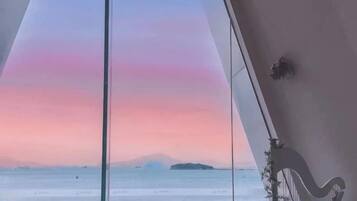 A room with a view of the sea and a sunset.