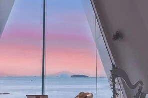 Una habitación con vista al mar y al atardecer.