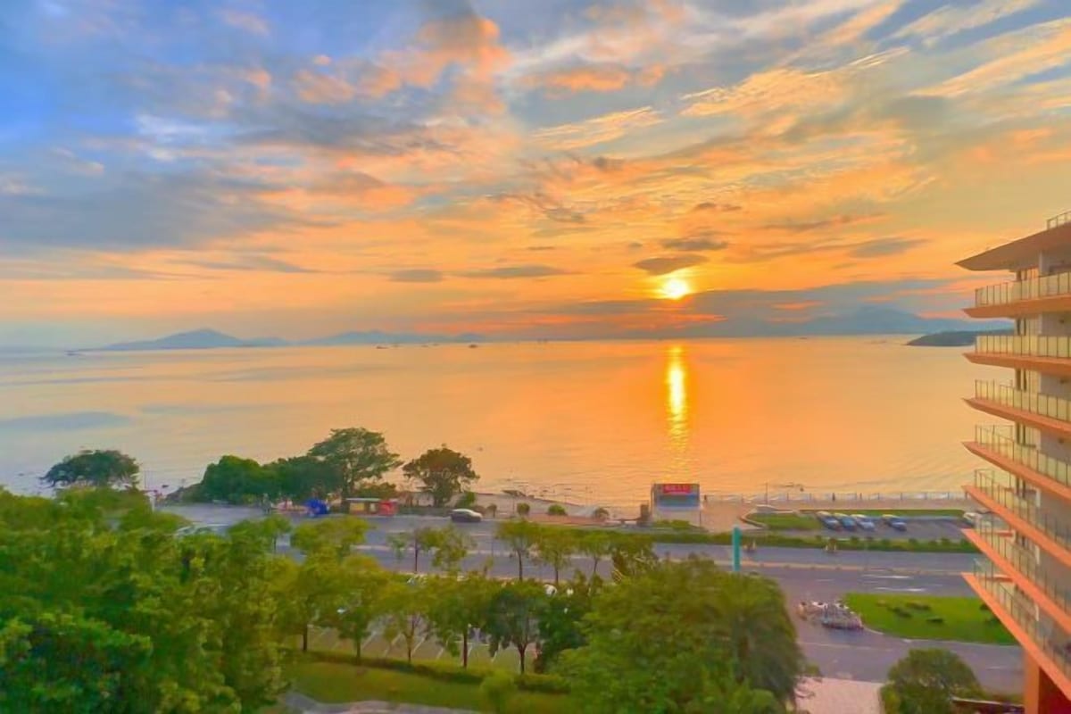 A sunset over a body of water with a view of a parking area and buildings.