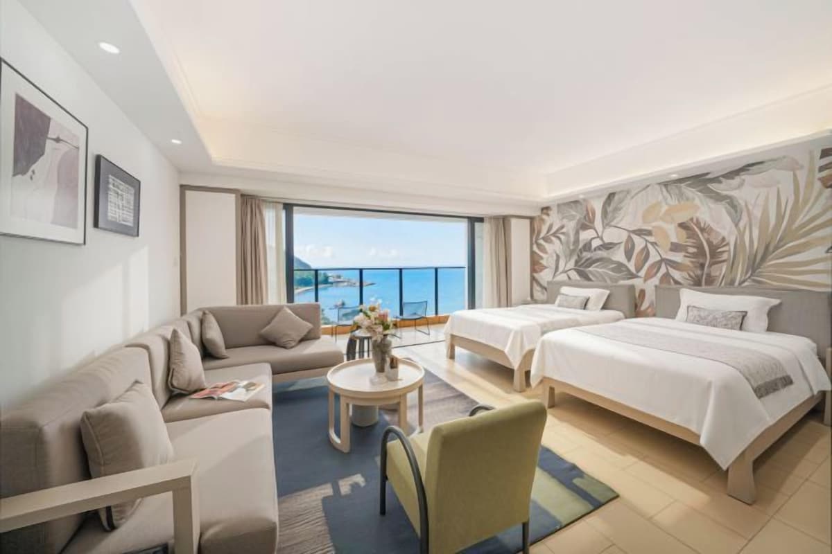 A hotel room with a balcony, a sofa, a bed, and a coffee table.