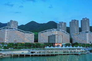 A waterfront hotel with multiple high-rise buildings, a dock, and a mountainous backdrop. - Island Skylight Resort (Huidong)