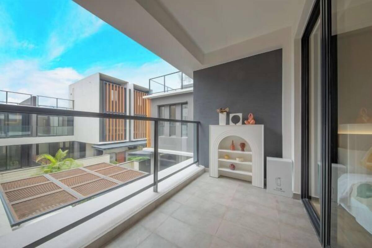 A modern apartment with a balcony, a fireplace, and a view of neighboring buildings.