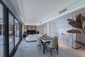 A modern, well-lit living room with a dining area, large windows, and a kitchen with white cabinets. - Island Skylight Resort (Huidong)