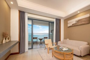 A modern living room with a sofa, a round coffee table, and a balcony with a view of the sea. - Island Skylight Resort (Huidong)