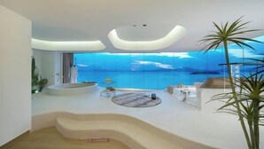A modern living room with a curved staircase leading to a balcony overlooking a body of water. - Island Skylight Resort (Huidong)