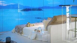 A bedroom with a large window, a bed, a bedside table, and a chair. - Island Skylight Resort (Huidong)