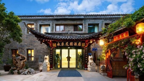 A traditional Chinese-style building with a tiled roof, stone facade, and a sign reading "永乐花园酒店". - Yongle Inn (Yangzhou)
