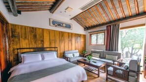 A room with a bed, a sofa, a coffee table, and a view of the outdoors. - Yongle Inn (Yangzhou)