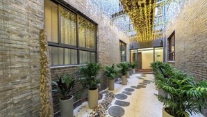 A courtyard with a brick wall, potted plants, a stone pathway, and hanging lights. - Yongle Inn (Yangzhou)
