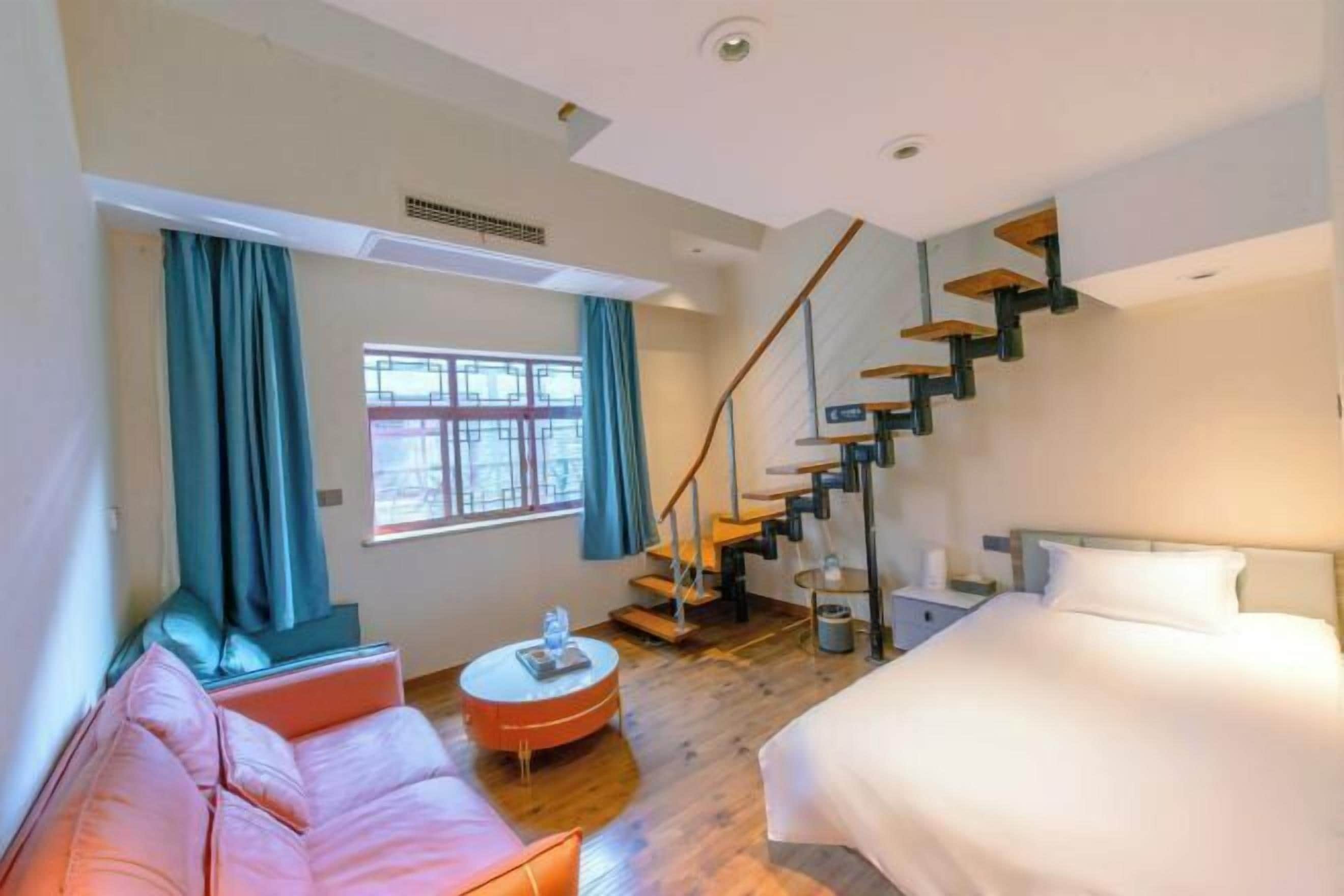 Een moderne hotelkamer met een trap, een bed, een bank en een ronde salontafel.