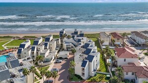 A coastal hotel with multiple buildings, a swimming pool, and a view of the ocean.