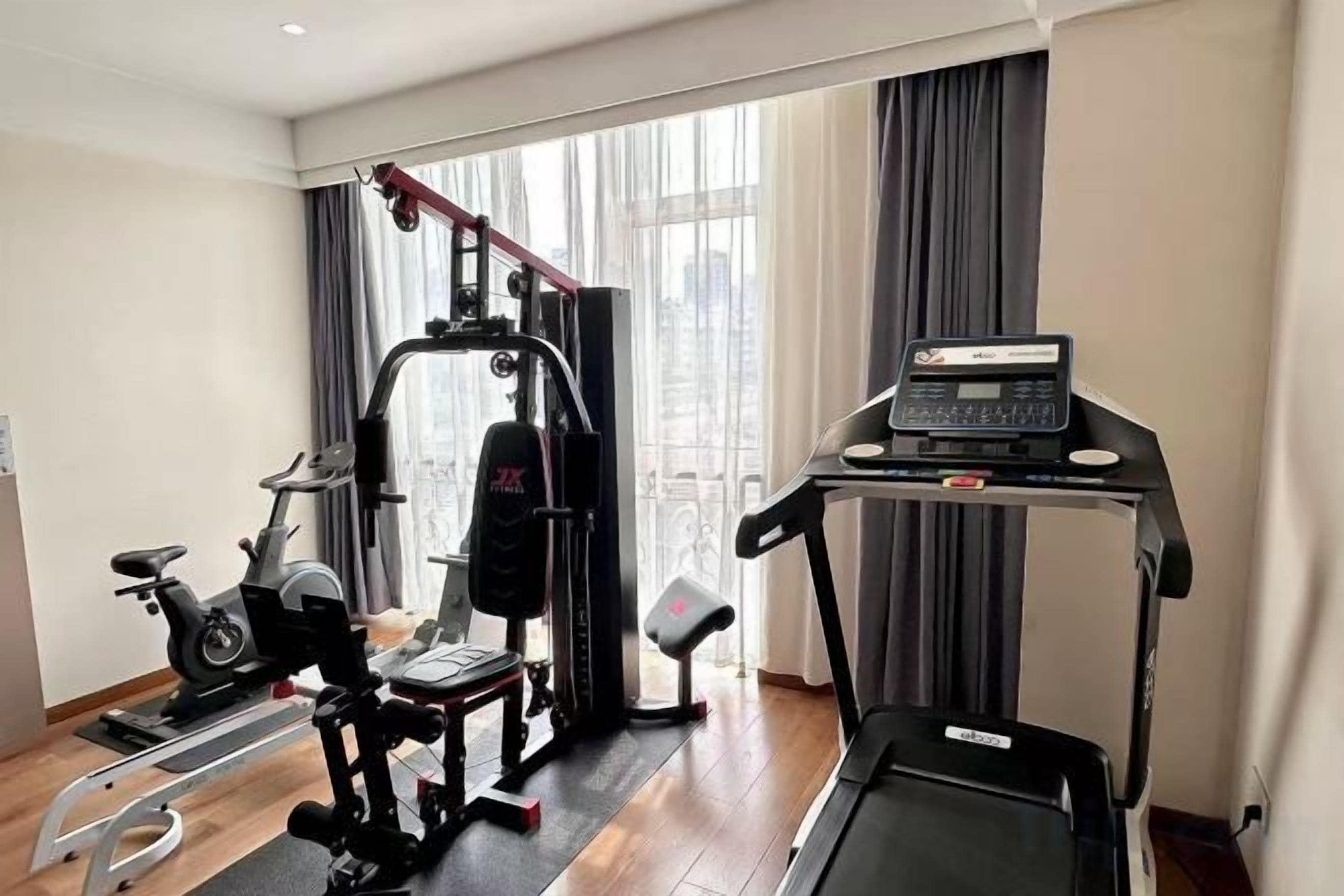 Un gimnasio en casa con cinta de correr, elíptica y máquina de pesas.